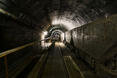 Railroad tracks in illuminated tunnel