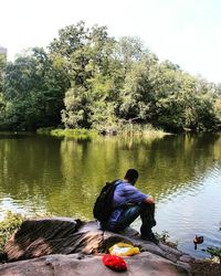 Rear view of people sitting on lakeshore