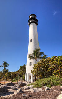 Low angle view of lighthouse by building against sky