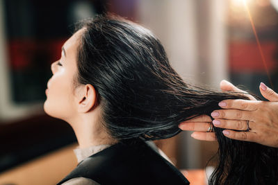 Cropped hands of hairdresser applying liquid to customer hair