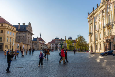 People on street amidst buildings in town against sky
