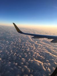 Airplane flying over sea against sky during sunset