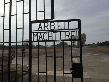 Information sign on metal gate by building against sky