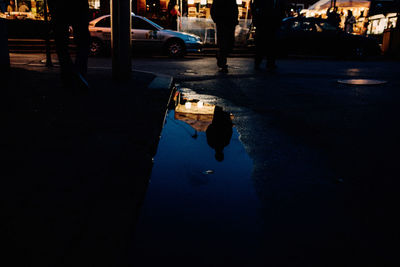 Reflection of people walking on road in city