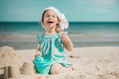 Full length of girl making sandcastles while sitting on beach