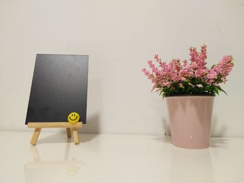 Flower vase by blackboard on table at home