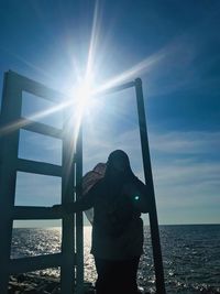 Woman standing by sea against sky