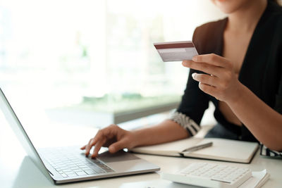 Midsection of woman using laptop on table