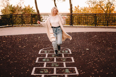 Young woman playing hopscotch in park during autumn