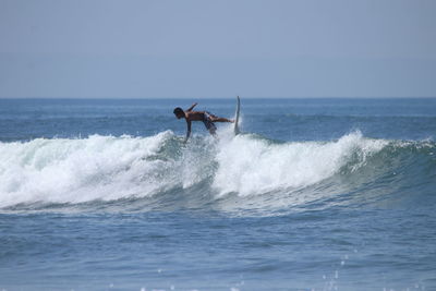 Man surfing in sea against sky