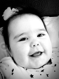 Close-up portrait of baby girl smiling while lying on bed