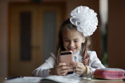 Cute girl using mobile phone on table at home