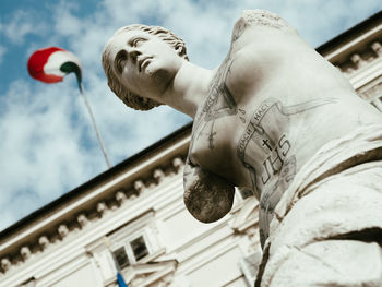 Low angle view of statue against building against sky