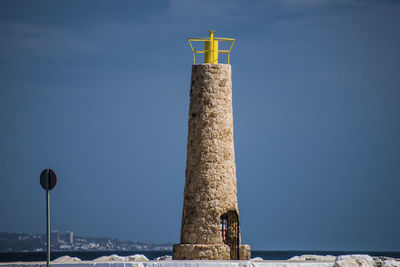 Cross against blue sea and building against clear sky