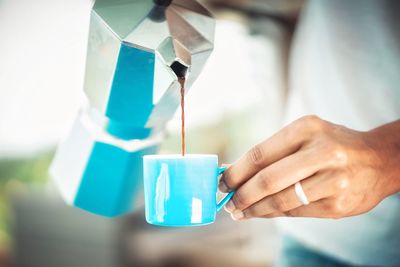 Close-up of hand pouring coffee in cup