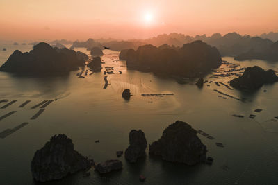 Rocks in sea against sky during sunset