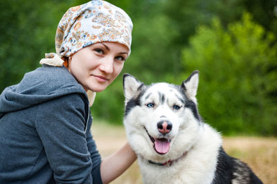 A young girl while walking in the park with a dog, hugging the dog husky and kissing.