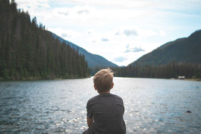 Rear view of boy looking at lake against mountains