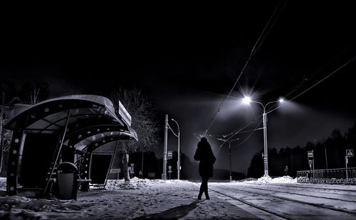 Silhouette woman waiting for tram during winter at night