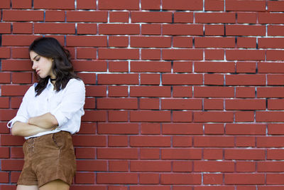 Woman standing against brick wall