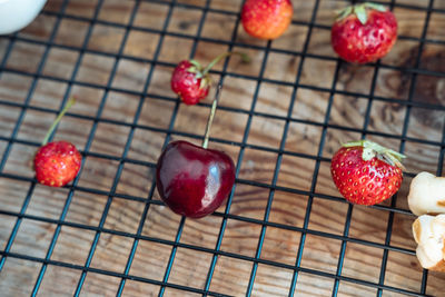 Fresh cherries and strawberries on a wooden table, on a black grid, top view