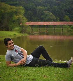 Portrait of smiling man reclining against lake
