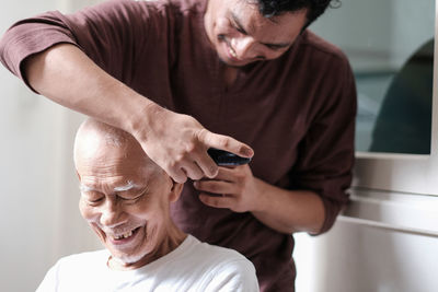 Smiling man cutting father hair