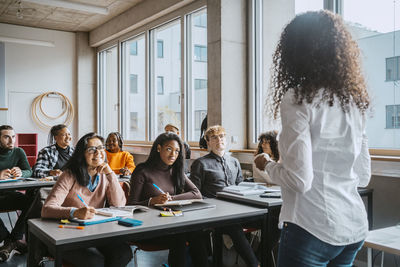 Multiracial students listening to professor teaching in classroom at community college