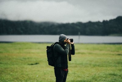 Man photographing on field against sky