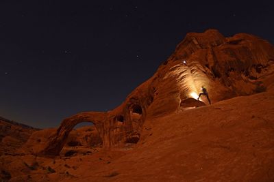 Low angle view of man standing on rock formation at night