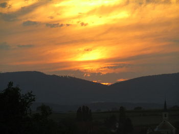 Scenic view of silhouette mountains against orange sky