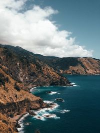 Scenic view of sea by mountains against sky