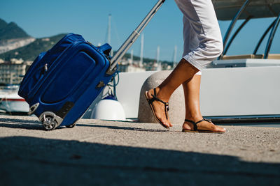 Low section of woman pulling suitcase