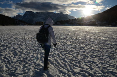 Rear view of man walking on snow covered mountain