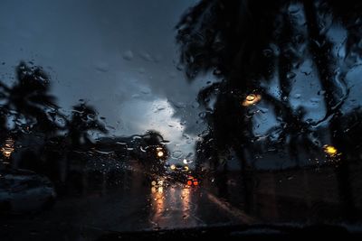 Wet cars on illuminated road during rainy season