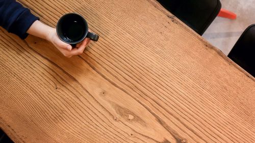 High angle view of person holding umbrella on wooden table