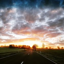 Road by landscape against sky during sunset