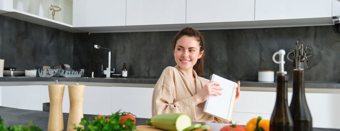 Portrait of young woman sitting in kitchen