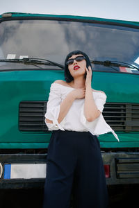 Young woman in sunglasses standing against truck