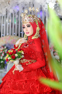 Portrait of beautiful bride wearing red traditional clothing standing in wedding ceremony