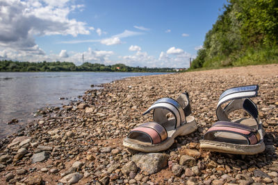 High angle view of shoes on rocks at beach against sky