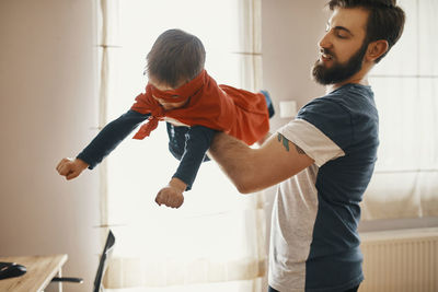 Father playing with his little son dressed up as a superhero