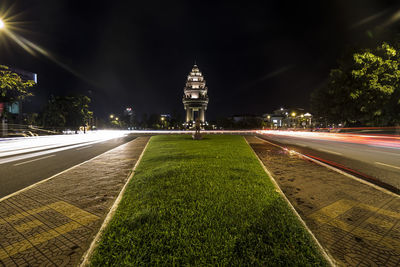 Light trails on illuminated city against sky at night