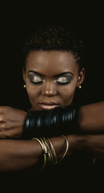 Close-up portrait of young woman against black background