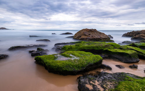 Rocks on sea shore against sky