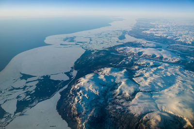 Aerial view of sea and snowcapped mountain against sky