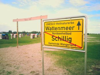 Information sign on field against sky