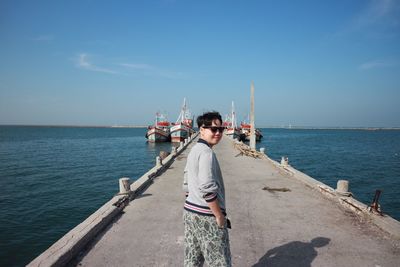 Portrait of woman standing on pier over sea