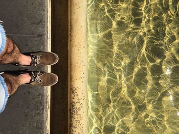 Low section of man standing by water's edge