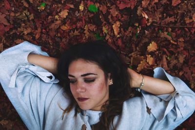 Young woman lying down with autumn leaves